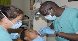Dentista e assistente examinando a boca do paciente - Você conhece o SINOG e sabe qual é sua importância?