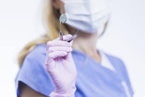 Dentistas segurando um instrumento odontológico - Entenda qual é a relação entre perícia criminal e odontologia
